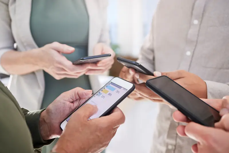 Mehrere Menschen halten ihre Smartphones nebeneinander in den Händen